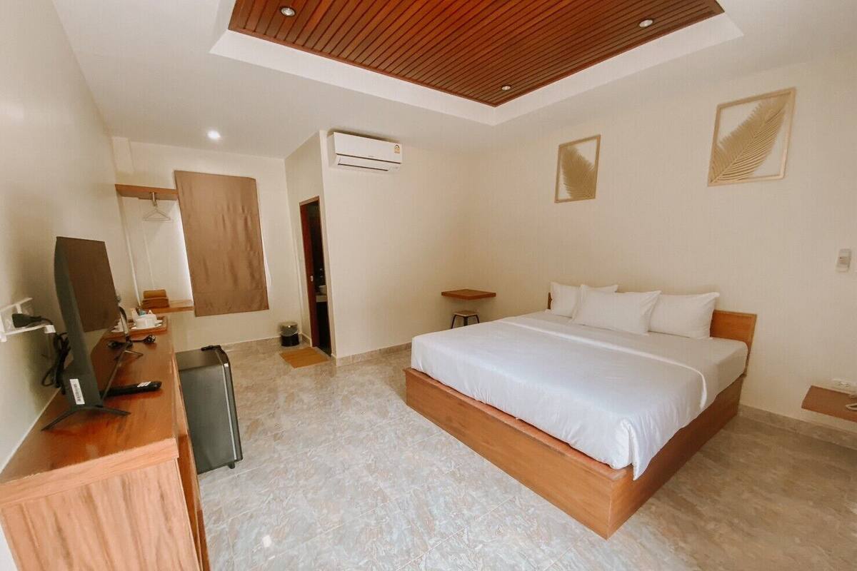 Quarto de hotel com uma cama grande, uma escrivaninha com um computador, ar condicionado e um espelho.