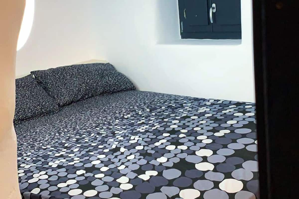 Una habitación pequeña y funcional con cama, ventana y puerta.