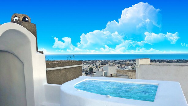 A rooftop pool with a clear view of the sea and cityscape. - The Luna Suites (Santorini)