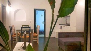 A modern living room with a dining area, a kitchen, and a view of the outdoors. - The Luna Suites (Santorini)