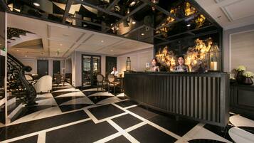 A lobby with a black and white checkered floor, a reception desk, and a staircase.