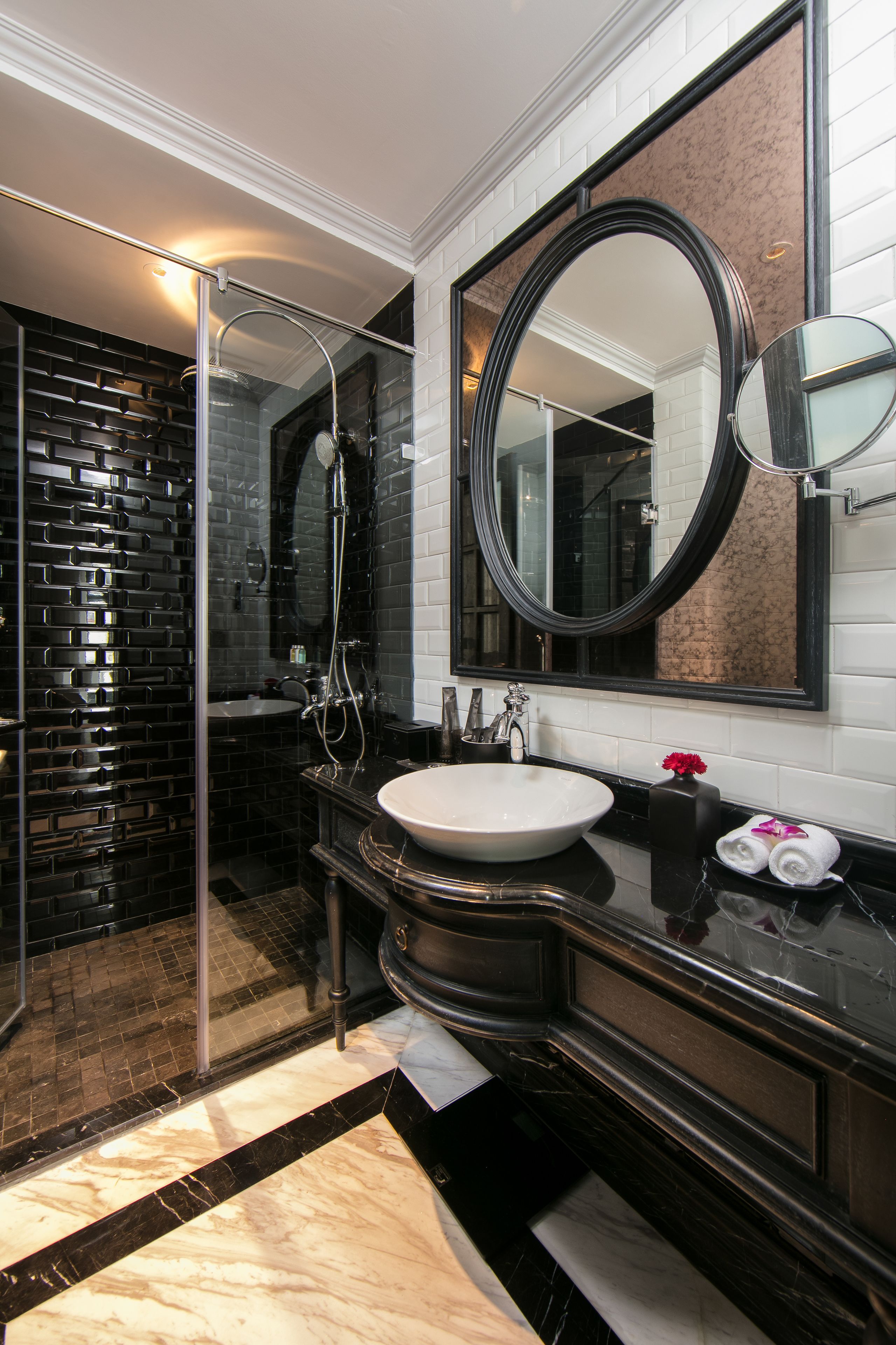 Un baño moderno con cabina de ducha de vidrio, un espejo grande y suelo de baldosas de mármol.