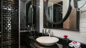 Un baño moderno con cabina de ducha de vidrio, un espejo grande y suelo de baldosas de mármol.