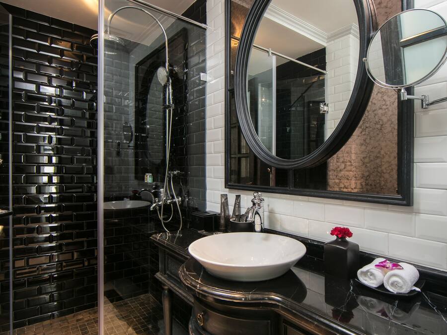 Un baño moderno con cabina de ducha de vidrio, un espejo grande y suelo de baldosas de mármol.