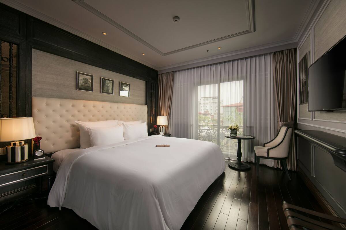 Ein Hotelzimmer mit einem großen Bett, einem Fernseher, einem Sessel und einem kleinen Tisch.