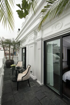 A balcony with two chairs, a table, and a large potted plant. - La Sinfonia Citadel hotel and Spa (Hanoi)