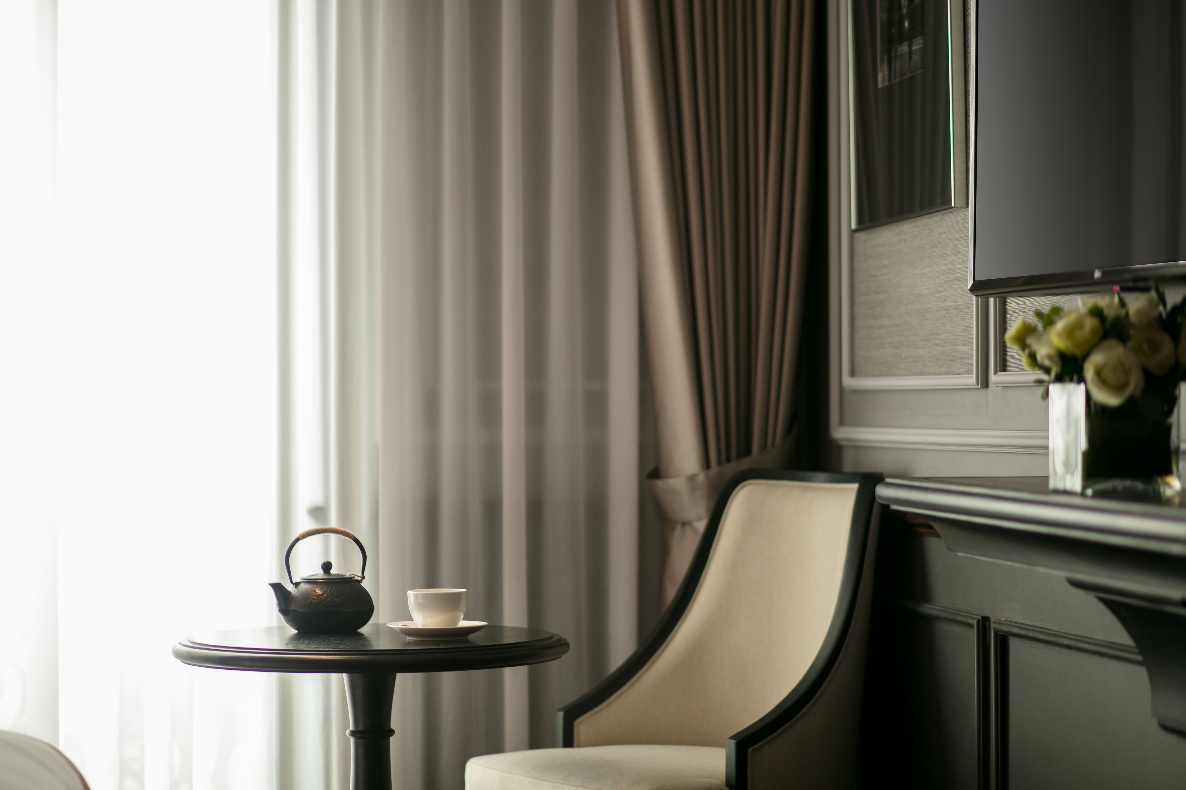 A room with a round table, a chair, a teapot, and a cup.
