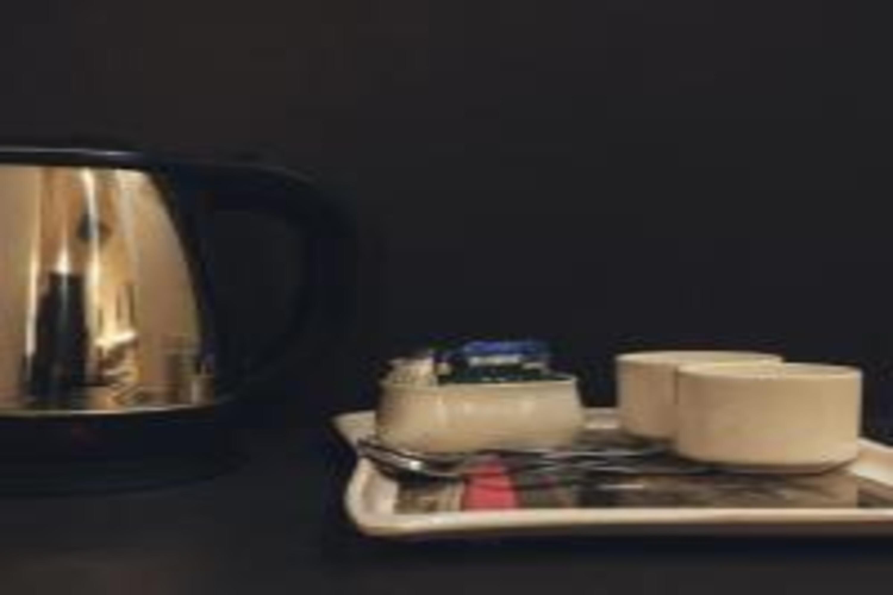 Ett bricka med en tekanna, en liten behållare och två koppar, troligen avsedda för te eller kaffe.