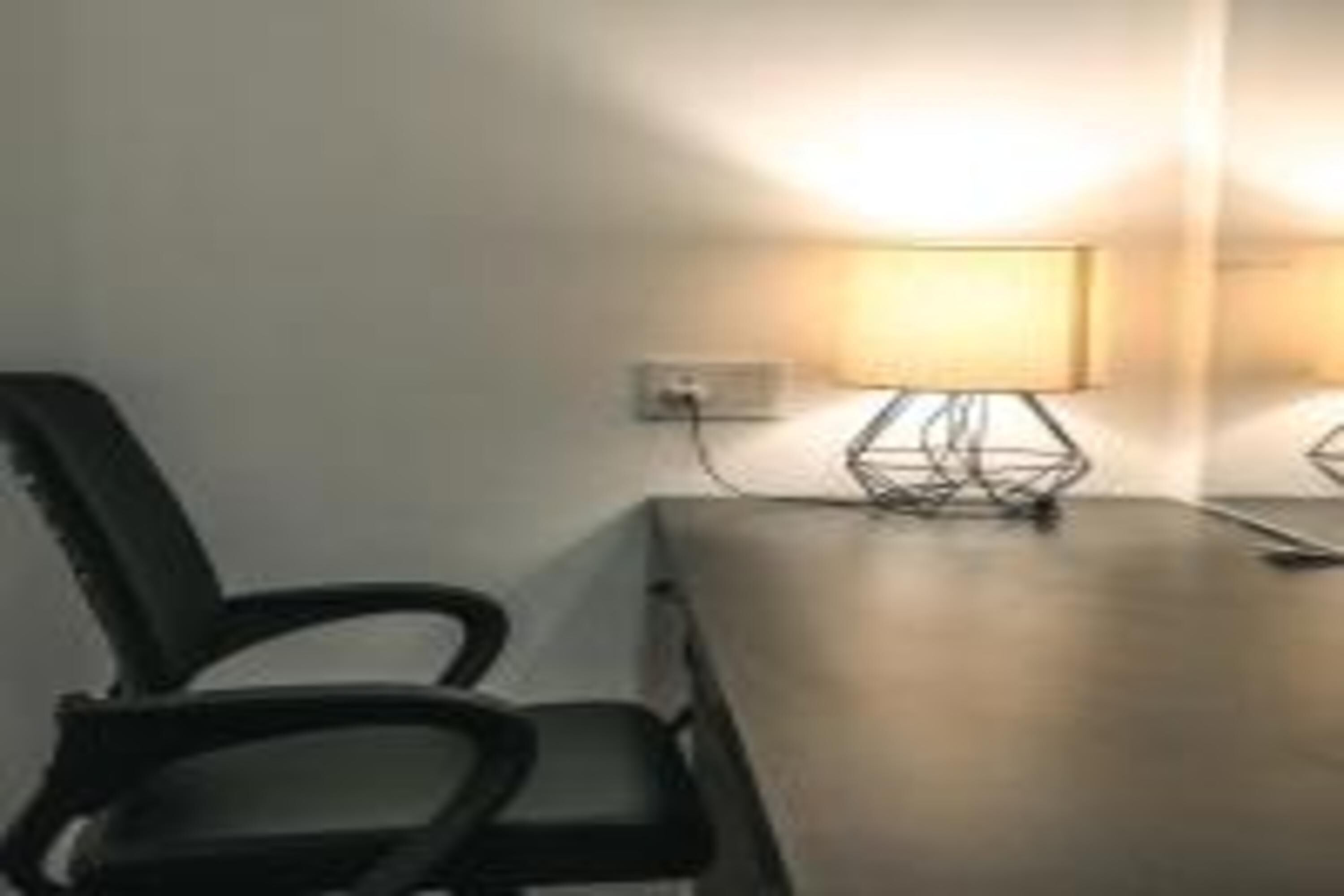 A room with a single black chair, a table, and a lamp.