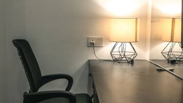 Una mesa de conferencias con una silla, una lámpara y un enchufe en la pared.