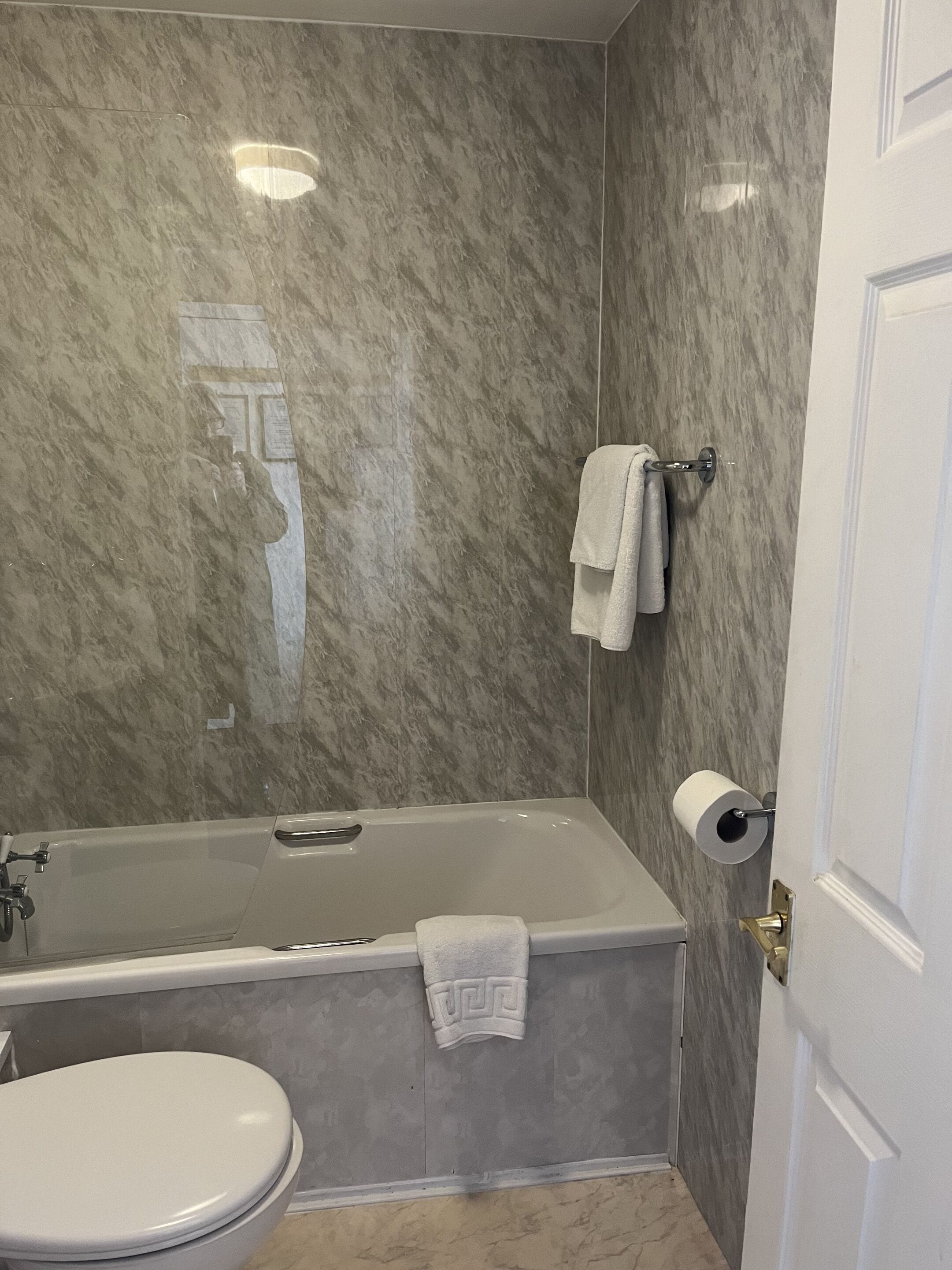 Un baño con bañera, inodoro y paredes de mármol.