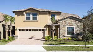 Une maison à deux étages avec une façade beige, un mur extérieur en pierre sur le côté droit et un garage avec une porte blanche.