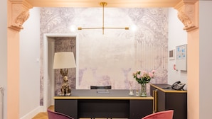 A reception desk with a modern design, a black desk, a lamp, and a vase with flowers. - 3110 ArtHotel (Florence)