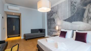 Habitación de hotel con cama, sofá, escritorio y pared con un mural texturizado.