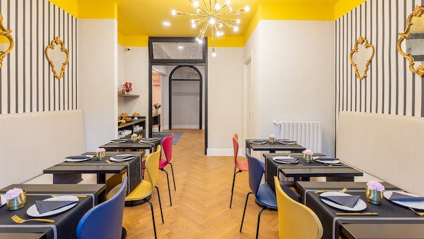 A restaurant with multiple tables and chairs, a central chandelier, and striped walls. - 3110 ArtHotel (Florence)