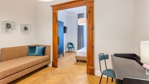 A modern living room with a sofa, a dining table, and a wooden door leading to another room. - 3110 ArtHotel (Florence)