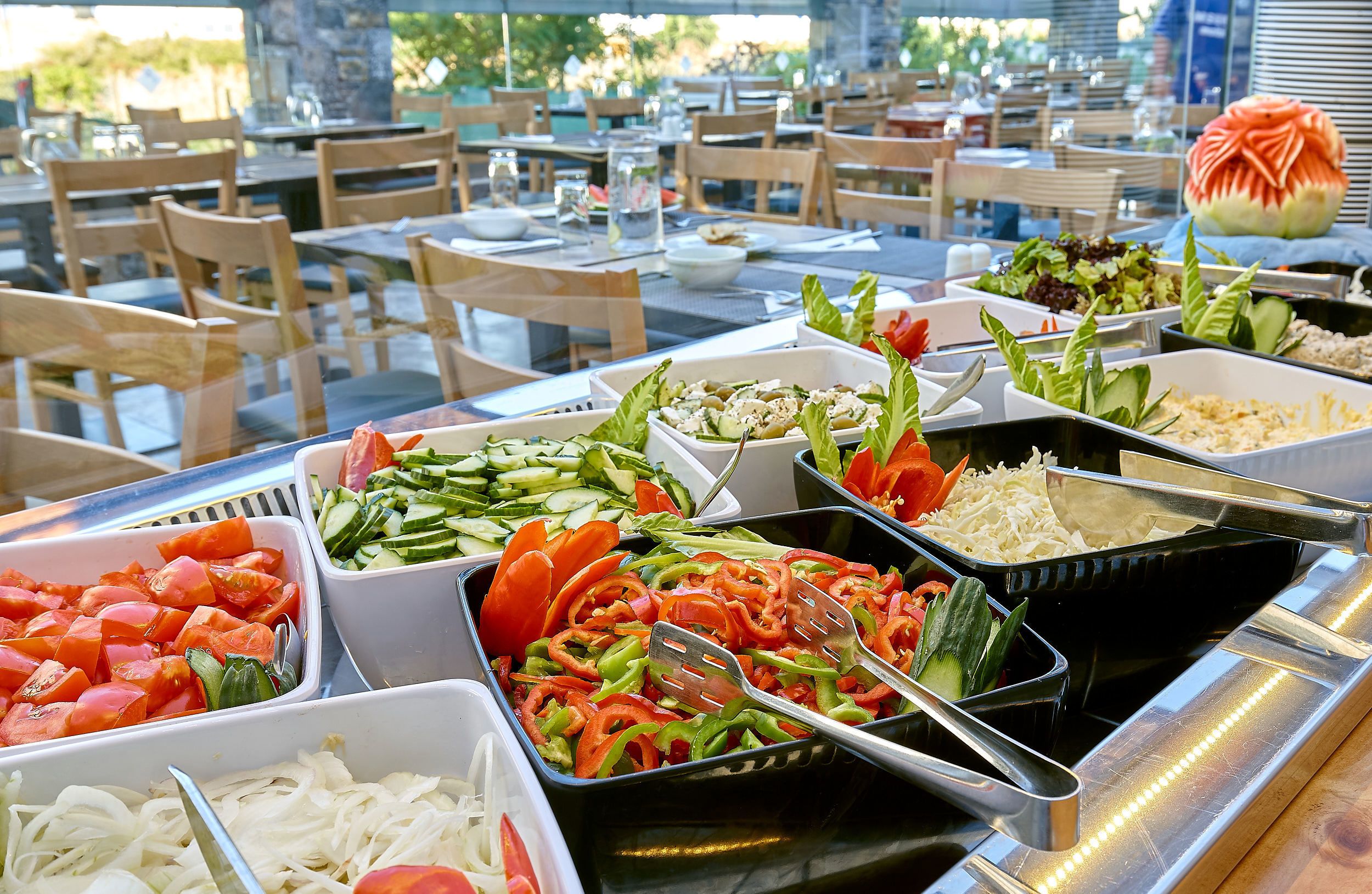 A buffet with various food items including sliced vegetables, salads, and rice.