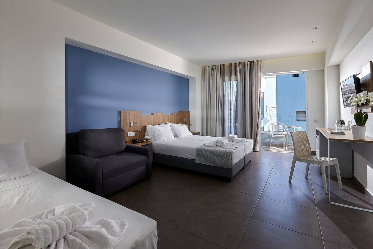 A hotel room with a bed, a sofa, a desk, and a chair.