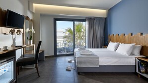 Una habitación de hotel moderna con una cama grande, un escritorio con televisor de pantalla plana, una silla y vistas a palmeras a través de un ventanal corredero.