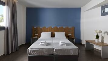 A double bed with two pillows, a wooden headboard, a bedside table, and a bench.