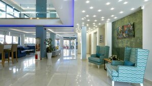 Un vestíbulo espacioso con techo alto, mobiliario moderno y un amplio ventanal que proporciona luz natural.