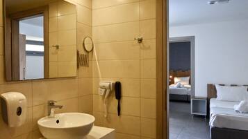 A hotel bathroom with a sink, mirror, hairdryer, and phone.