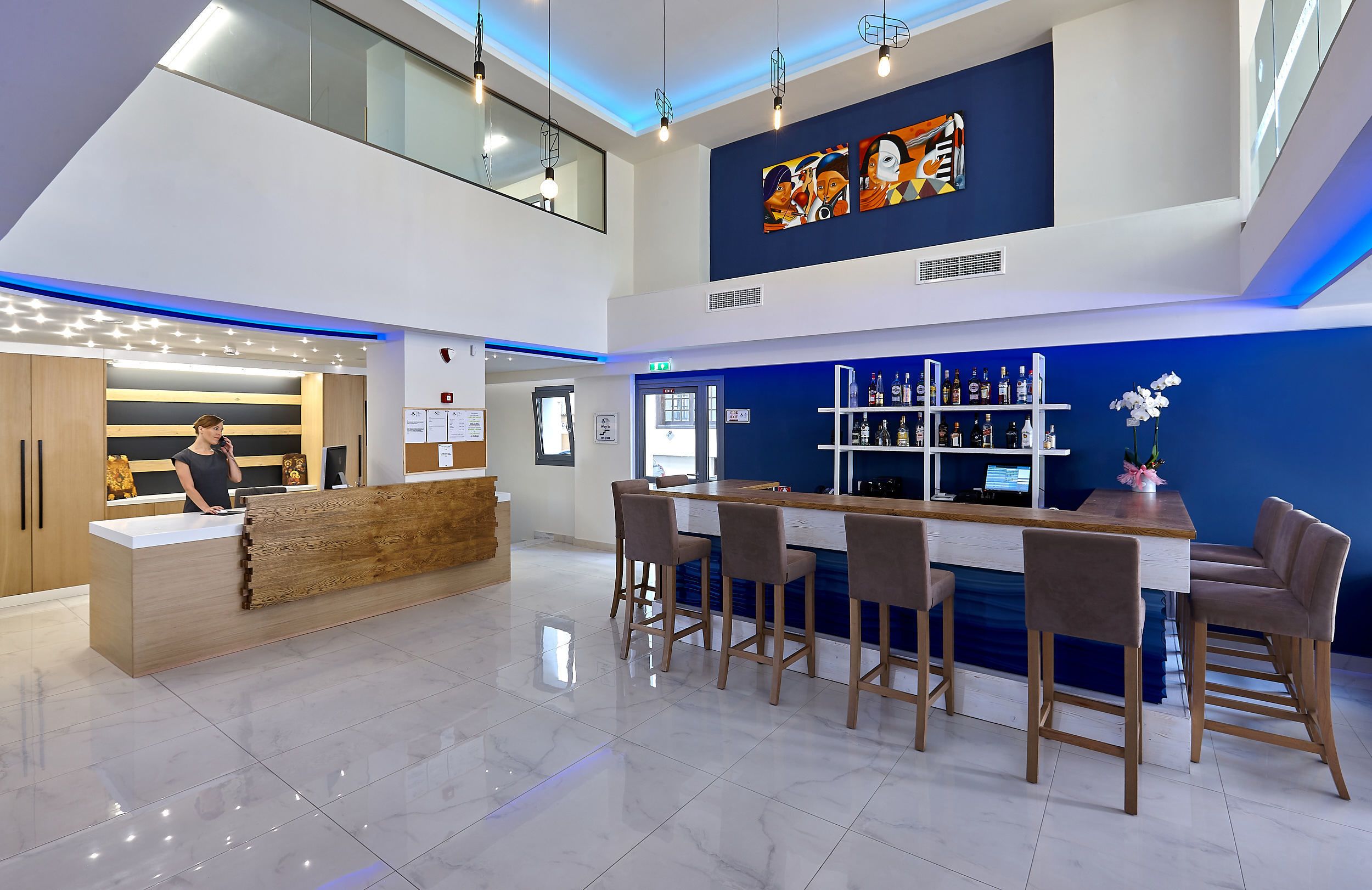 A modern bar area with a wooden counter, bar stools, and a blue accent wall.
