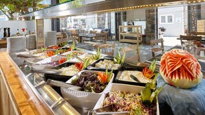 Un bufé con diversas opciones de comida y una gran sandía tallada como pieza central.