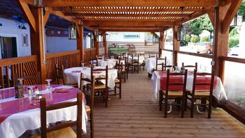 Een openluchtrestaurant met houten tafels en stoelen, overdekt door een houten pergola.