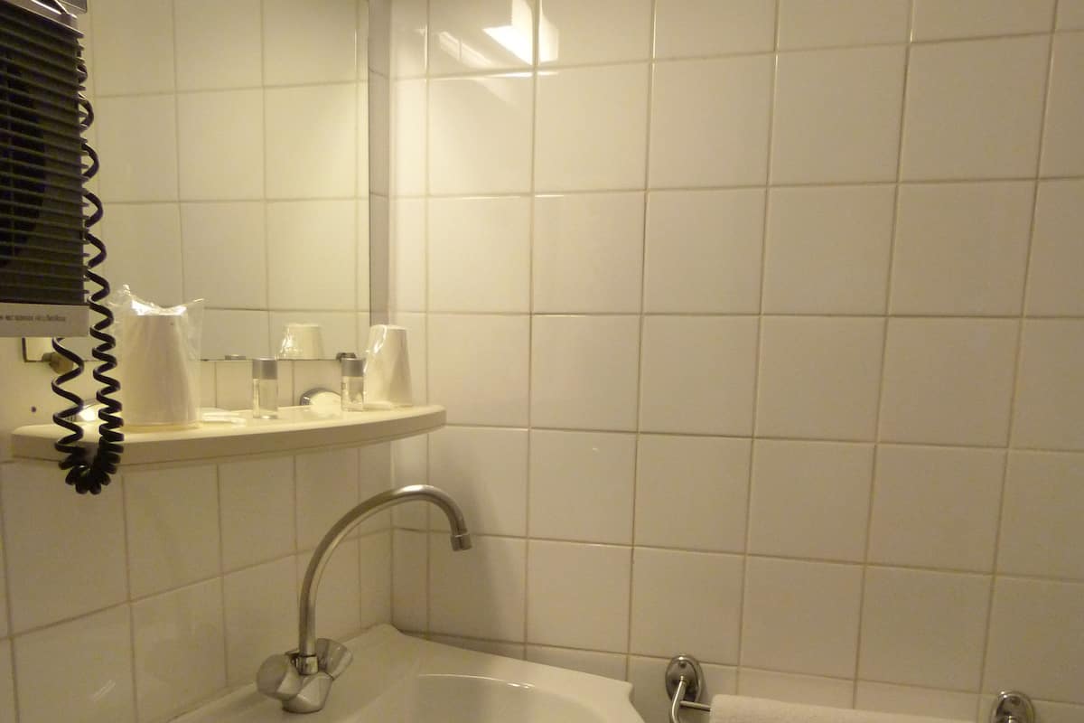 Une salle de bain avec un lavabo blanc, un miroir et un porte-serviettes.