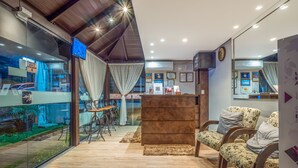 A modern interior with a reception desk, seating area, and a large window overlooking a street. - Alameda Felice Hotel (Gramado)