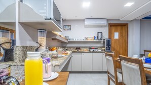 A modern kitchen with a granite countertop, a coffee maker, a toaster, and a breakfast bar. - Alameda Felice Hotel (Gramado)