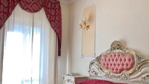 A bedroom with a large bed, a chandelier, a mirror, and a nightstand. - Colosseo Rooms Imperial Rome (Rome)