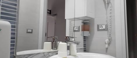 A bathroom with a marble sink, a mirror, a hairdryer, and a towel rack.