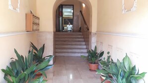 A hallway with a marble floor, flanked by potted plants, leading to a staircase. - Colosseo Rooms Imperial Rome (Rome)