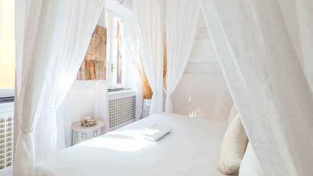 A bedroom with a bed, white curtains, a bedside table, and a window with a view. - Sweet Navona (Rome)