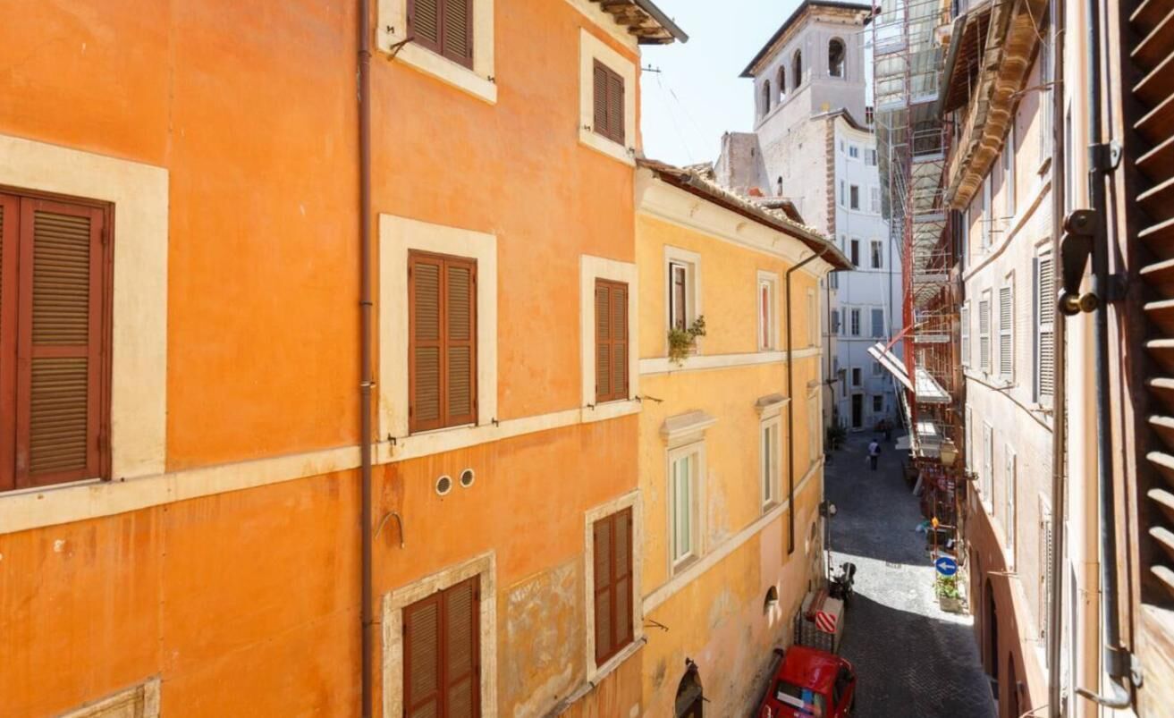 Una calle estrecha flanqueada por edificios, con arquitectura tradicional y contraventanas en las ventanas.