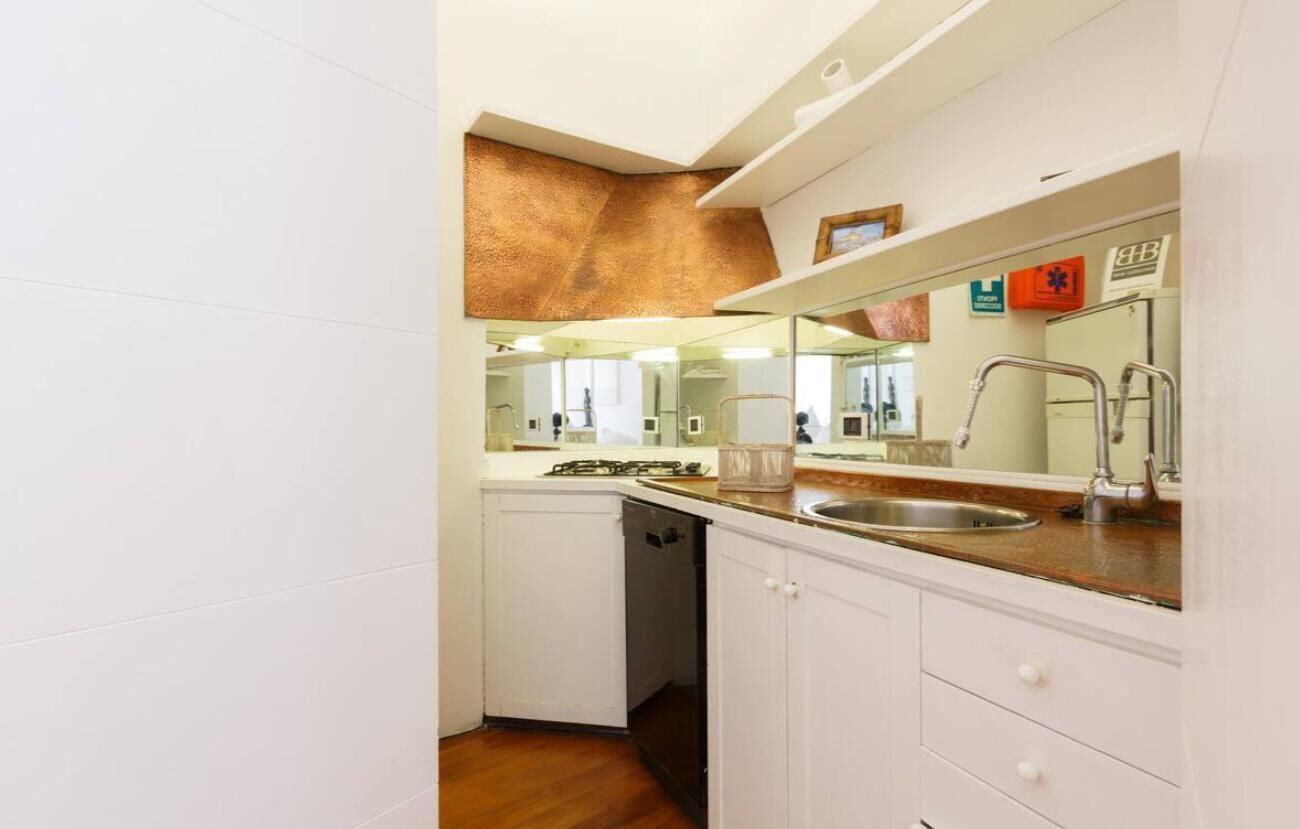 A compact kitchen with white cabinets, a stainless steel sink, and a built-in oven.
