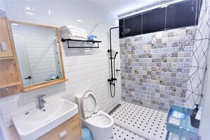 A modern bathroom with a white sink, a toilet, a shower, and a tiled shower wall. - Childhood Days (Taitung)