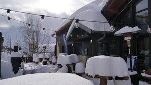 A snow-covered outdoor area with wooden structures and string lights. - Ho36 Les Menuires (Les Belleville)