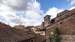 A traditional European town with terracotta-tiled roofs, a bell tower, and potted plants on balconies. - Navona Deluxe Jolie (Rome)