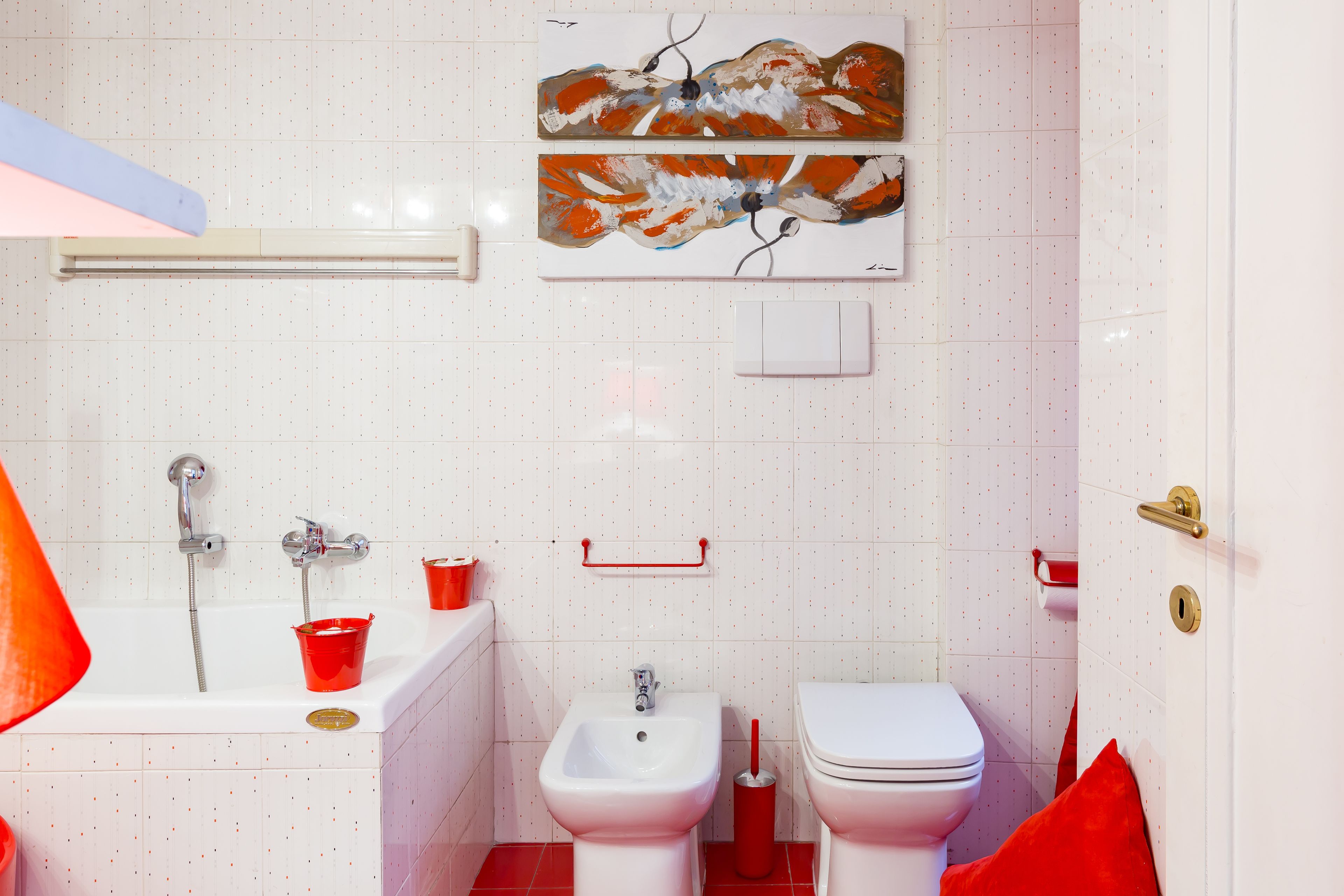 A bathroom with a bathtub, bidet, toilet, and a red towel.