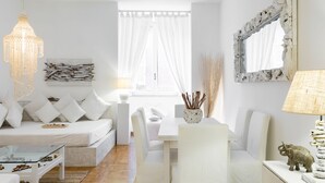 Una sala de estar moderna con decoración blanca, un sofá, una mesa de comedor y sillas.