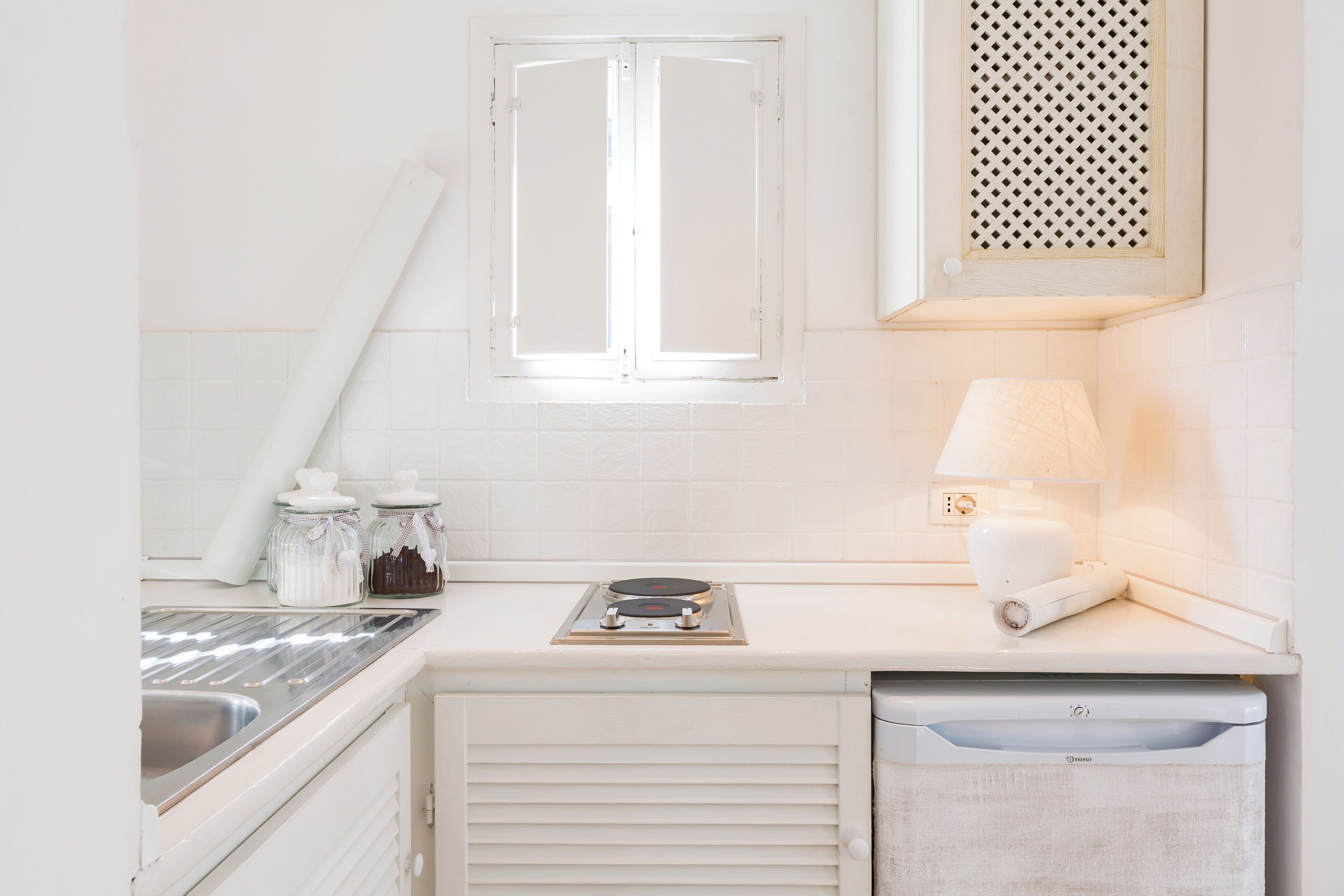 A kitchen with white cabinets, a window, a stove, and a dish drying rack.