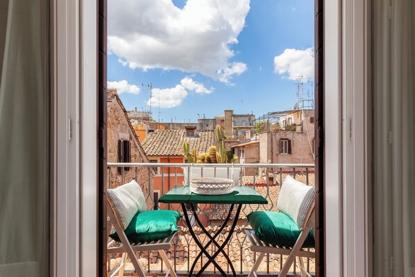A balcony with two chairs, a table, and a view of the cityscape.