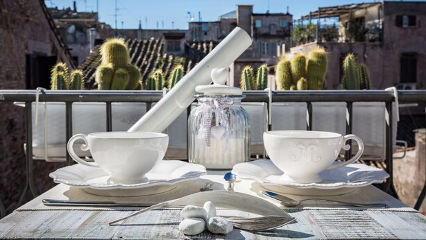 A table with two white cups and saucers, a jar with a heart-shaped lid, and a spoon.