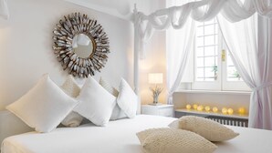 A bedroom with a bed, white bedding, a decorative mirror, and a bedside table with a lamp. - Domus Colosseo (Rome)