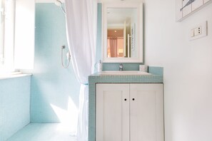 A bathroom with a shower, a sink, and a mirror. - Domus Colosseo (Rome)