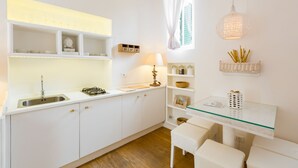 A modern kitchen with white cabinetry, a glass-top table, and a hanging light fixture. - Domus Colosseo (Rome)