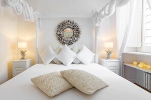 A bedroom with a large bed, white bedding, a decorative mirror, and two bedside tables with lamps. - Domus Colosseo (Rome)